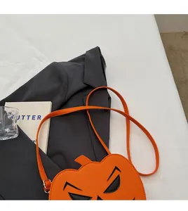 Detail of orange pumpkin crossbody bag with spooky face embroidery and long shoulder strap