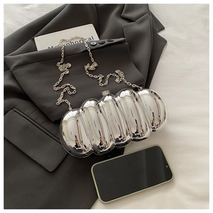 Silver metallic clutch bag with pleated ripple texture and elegant chain strap on a blazer