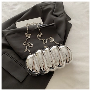 Macro view of silver wave patterned metallic evening bag on dark gray suit jacket