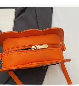 Macro view of bright orange pumpkin bag showing smooth golden metal zipper and texture