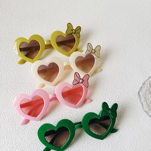 Detail view of heart-shaped kids sunglasses with bow accents in four pastel colors