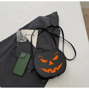 Detail of black PU pumpkin crossbody bag with orange Jack-o'-lantern face on white background