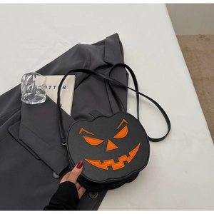 Detail of black pebbled leather pumpkin shoulder bag with bright orange jack-o'-lantern face