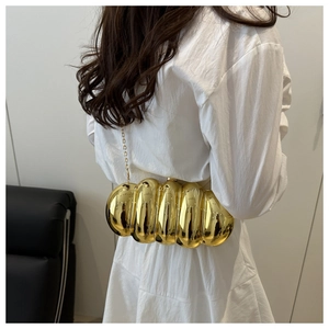Chic gold acrylic box bag with metallic texture shown on a white pleated dress