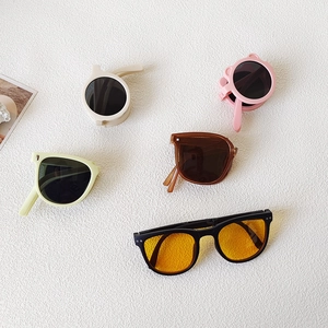 Foldable vintage children sunglasses in various colors and shapes on textured background