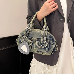Vintage blue denim shoulder bag with front pockets and heart charm shown on a model