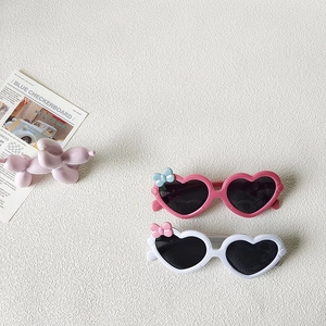 Lunettes de soleil coeur pour enfants roses et blanches avec nœuds sur fond blanc