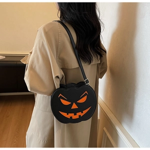 Detail of a Halloween pumpkin crossbody bag in black and orange leather on a model
