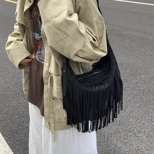 Black frosted suede crossbody bag with long tassels and adjustable strap shown on model