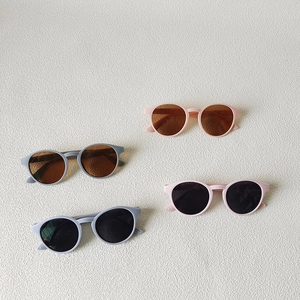 Kids round frame sunglasses in pink and blue colors on a white textured background