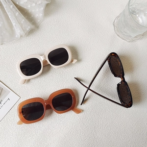 Three retro oval sunglasses in cream, amber, and tortoiseshell frames on a white surface