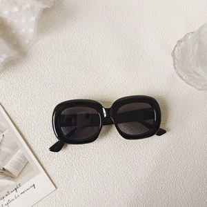 Flat lay of retro oval black sunglasses with UV protection on a minimalist aesthetic background