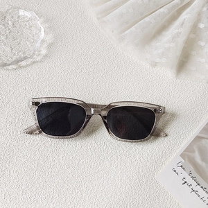 Détail de lunettes de soleil carrées avec monture grise transparente et verres gris foncé