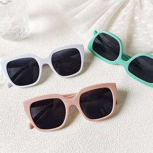 Macro shot of stylish square sunglasses in white, green, and pink colors on white texture