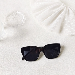 Flat lay of square black sunglasses on white lace and crystal textured background