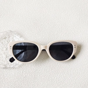 Détail de lunettes de soleil œil-de-chat rétro avec monture crème et rivets argentés