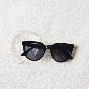 Détail de lunettes de soleil noires à monture complète avec verres UV400 sur un plateau