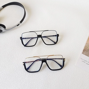 Classic oversized aviator sunglasses in black and black-gold frames on a white table