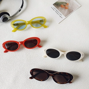 Retro oval sunglasses in various colors with silver rivets on a white textured background