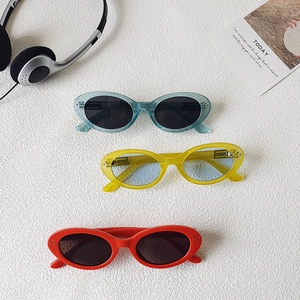 Three pairs of vintage oval sunglasses in blue yellow and red on stone background