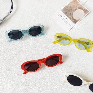 Detailed flat lay of retro oval sunglasses in blue, yellow, red, and off-white colors