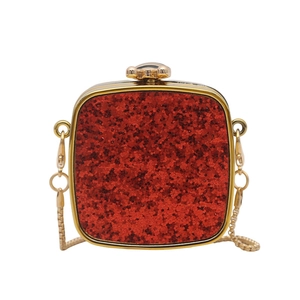 Macro detail of red sequin party clutch with gold metal frame and floral clasp