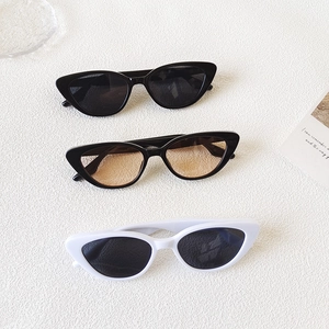 Three pairs of vintage cat-eye sunglasses in black and white colors on a textured surface