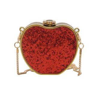 Macro shot of red sequin heart-shaped evening bag with gold metal frame and chain