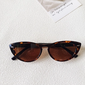 Top view of retro tortoiseshell cat-eye sunglasses with silver metal rivets on cream background