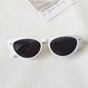 Flat lay of white cat eye sunglasses with grey lenses and silver metal dot accents