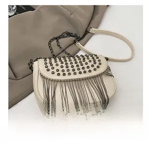 Détail du sac à bandoulière crème avec rivets métalliques et franges de chaînes