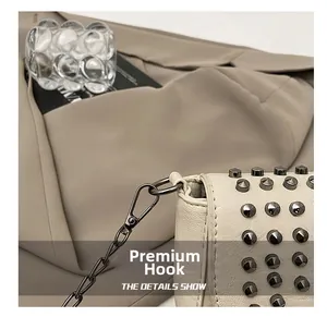 Détail du crochet métallique et des rivets gris sur le sac à bandoulière en cuir beige