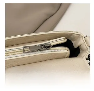 Détail de la fermeture éclair en métal et du cuir sur un sac selle beige