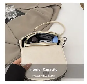 Détail de la capacité intérieure du sac bandoulière crème avec pompons métalliques