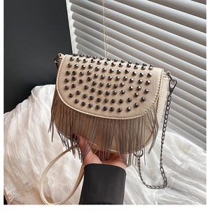 Détail du sac selle crème avec des clous métalliques et des franges de chaînes pendantes