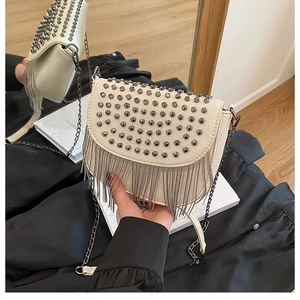 Détail du sac besace crème avec clous, franges en chaîne et texture en cuir