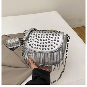 Détail du sac selle argenté orné de rivets punk et de longues franges en chaîne métal