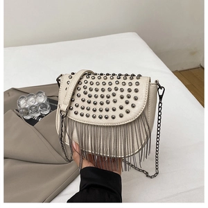 Détail du sac selle crème avec des rivets punk et des franges de chaînes métalliques