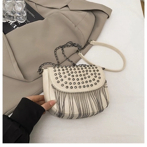 Détail du sac selle crème avec rivets métalliques vintage et franges à longues chaînes
