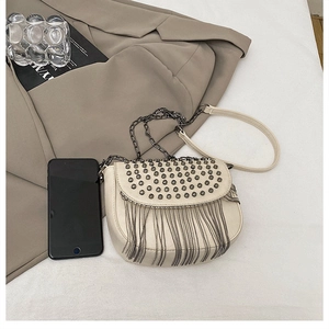 Détail du sac besace beige avec des clous argentés et des finitions à pompons chaînes