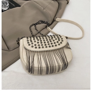 Détail du sac selle crème avec clous métalliques vintage et franges à chaînes longues