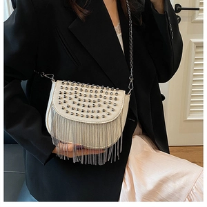 Détails des rivets argentés et franges métalliques sur un sac bandoulière blanc