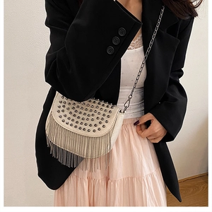 Détail du sac crème avec rivets argentés, franges métalliques et bandoulière chaîne