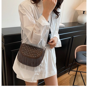 Détail du sac selle marron foncé avec clous métalliques, franges et bandoulière