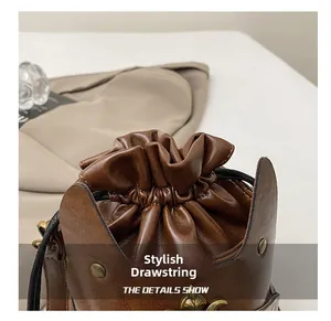 Detail view of caramel leather drawstring closure with retro bronze rivets and metal crest