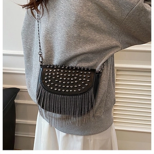Gros plan d'un sac besace noir avec clous argentés et franges en chaîne métallique