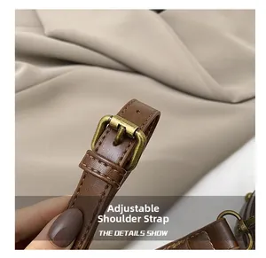 Détail de la bandoulière réglable en cuir marron avec boucle en bronze antique et couture