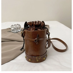 Detail of vintage cylindrical bucket bag featuring gold rivets and drawstring closure