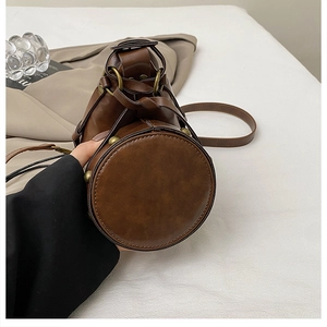 Macro shot of the round base of a brown vintage bucket bag with bronze stud details