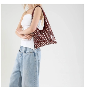 Close-up of a burgundy leather hobo bag with silver metallic studs worn by a model